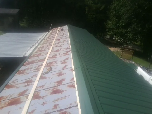 Old rusted panels beside newly installed green metal roofing — Wind Damage Roof Repair by Roofing Brothers in Harrogate