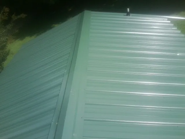 New green metal panels meeting at the ridge of a roof — Flat Roof Repair work by our crew in Harrogate