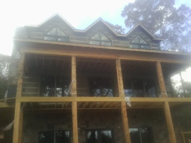 Dormers and porch framing on a large log home under construction — Roof Coating work by our crew in Harrogate