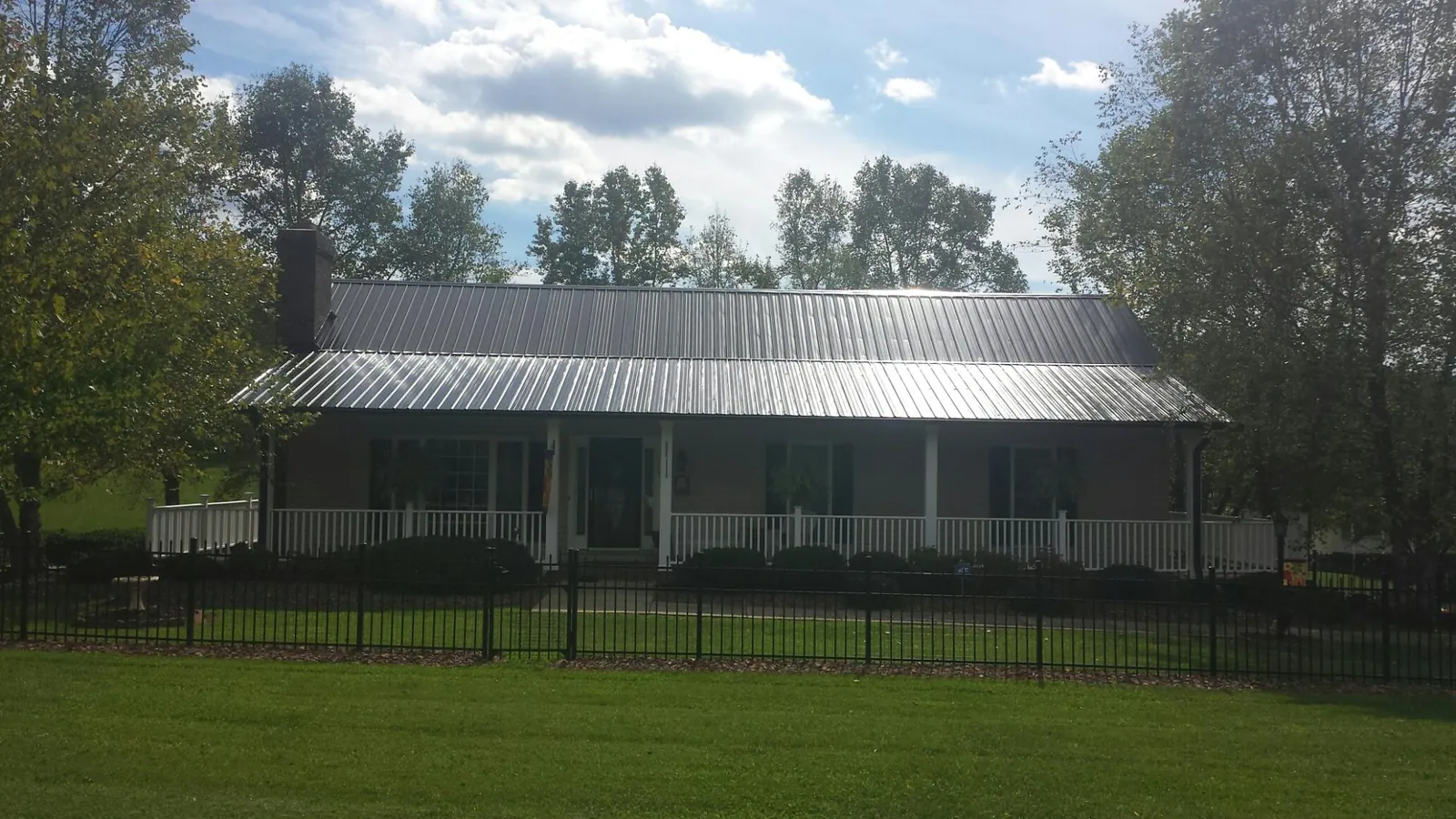 Gray metal roof on a brick ranch with a full width front porch — Gutter Guard Installation work by our crew in Harrogate