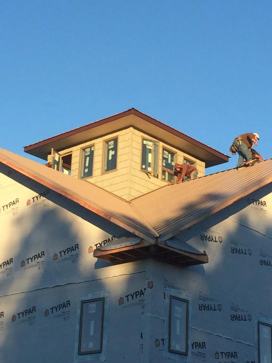 Roofers working around a rooftop cupola on a new metal roof at sunset — Roof Waterproofing in Harrogate by Roofing Brothers